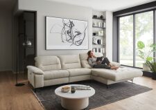 Sedací souprava CORTINA 2600_ sestava 4682_ rohové rozměry zleva 308 x 184 cm_ polohovatelné opěrky hlavy ve standardu_ ostatní volitelné funkce a polštáře za příplatek_ v látce Yelda natur_ foto s modelem_ obr. 2 Sedací souprava CORTINA 2600_ sestava 4682_ rohové rozměry zleva 308 x 184 cm_ polohovatelné opěrky hlavy ve standardu_ ostatní volitelné funkce a polštáře za příplatek_ v látce Yelda natur_ foto s modelem_ obr. 2